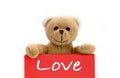 Love brown teddy bear holding with the two hands a red pink color note with the message Ã¢â¬ÅLove`